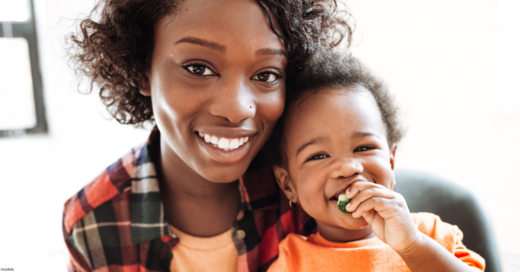 Smiling African American woman holding smiling baby