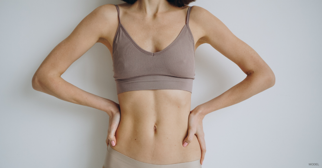 Woman with toned torso and hands on hips wearing brown bra top