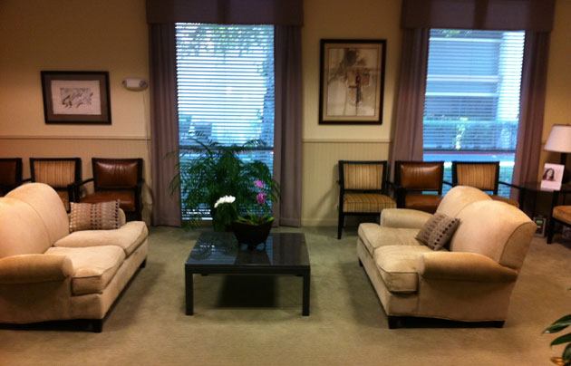 Sacramento waiting room with two couches facing a coffee table and chairs along a wall with windows