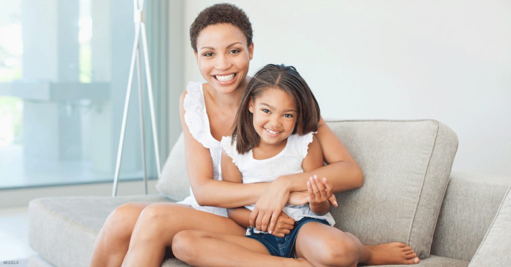 Smiling woman holding smiling girl in her lap