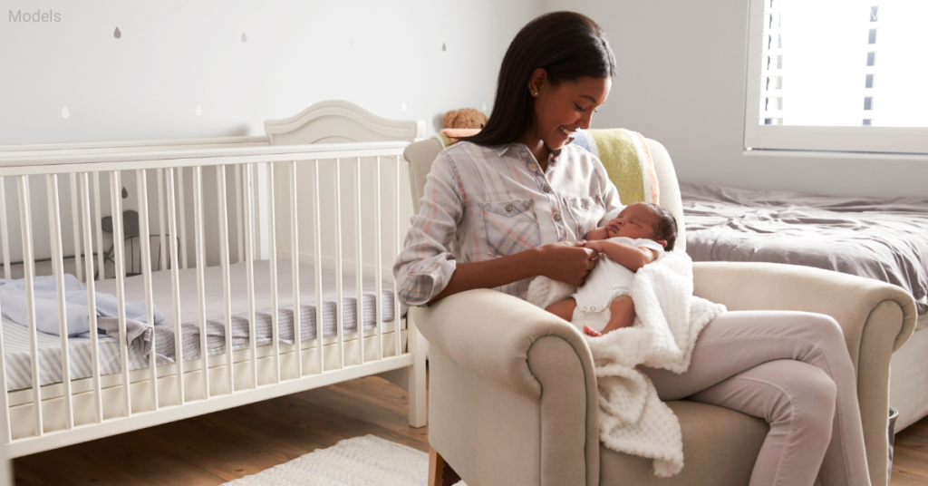 A woman sitting in a nursery with her baby in a rocking chair (models)